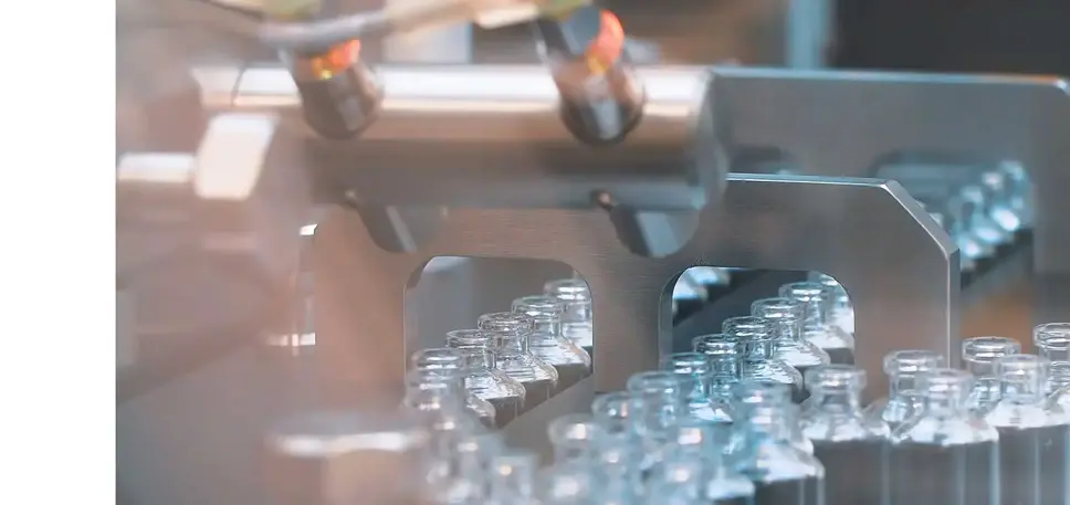 Pharmaceutical production line, crammed with empty glass vials running through a stainless steel machine