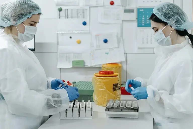 Two scientists working together, holding a set of vials