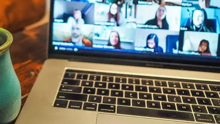 Open laptop showing a screen full of the faces of delegates on a video call