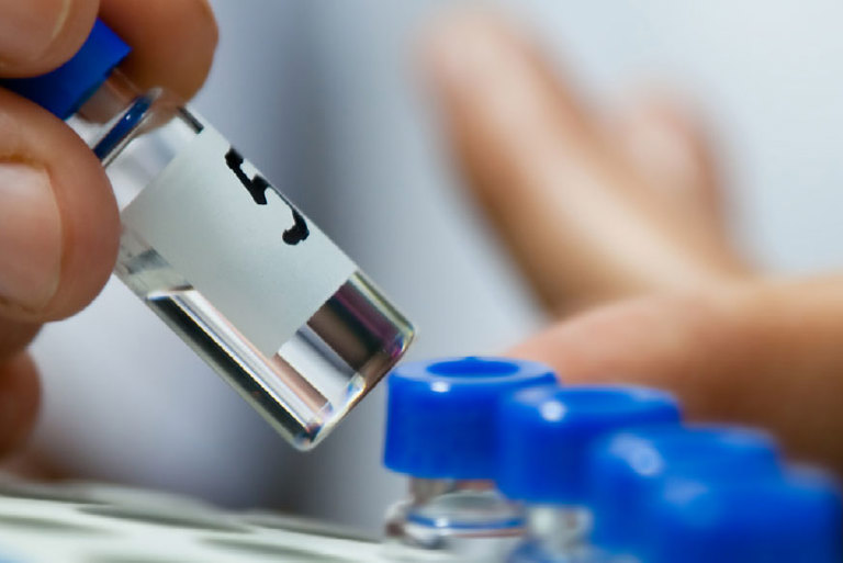 Close up a filled medicine vial being picked up