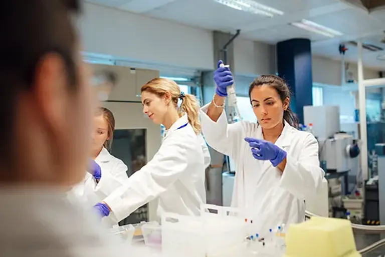 Three young scientists are seen working on a number of vials in the lab