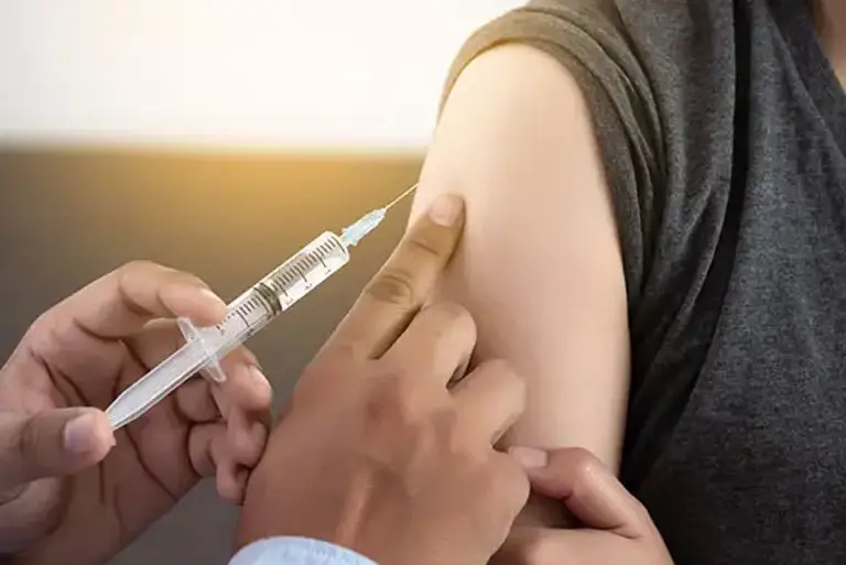 Healthcare professional about to inject into the shoulder of a patient