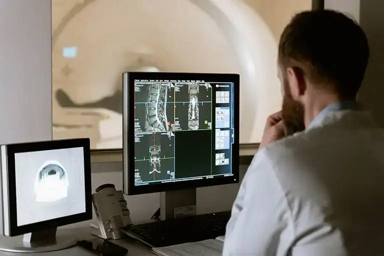 View from behind of a specialist examining the screen showing the MRI of a scan of the patient in the MRI